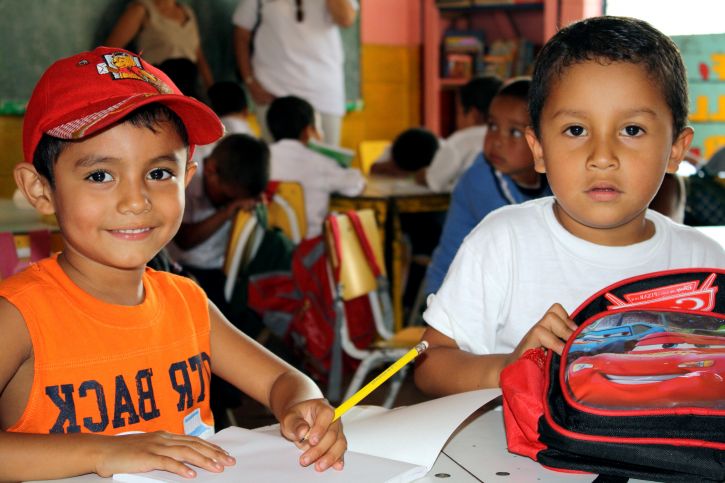 two-kindergarteners-in-marta-urrutias-kindergarten-class-at-centro-escolar-las-lajas-check-out-a-visitor-725x483